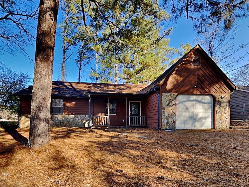 a red house with a garage with a tree in front of it