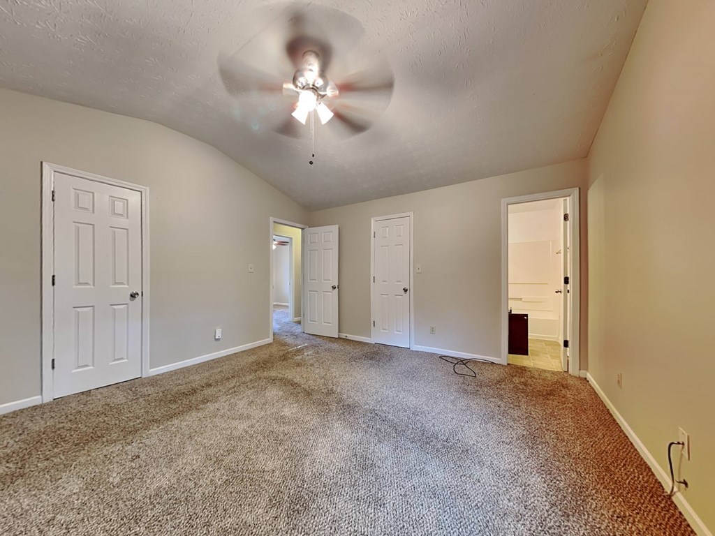 an empty living room with a ceiling fan