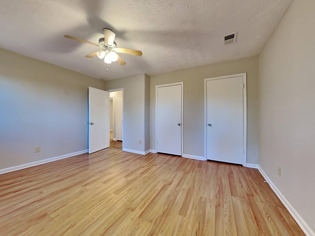 an empty living room with wood floors and a ceiling fan