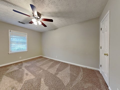 an empty bedroom with a ceiling fan and a window