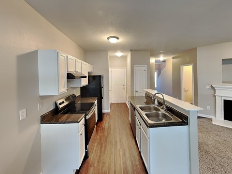 A kitchen with white cabinets and a black fridge.
