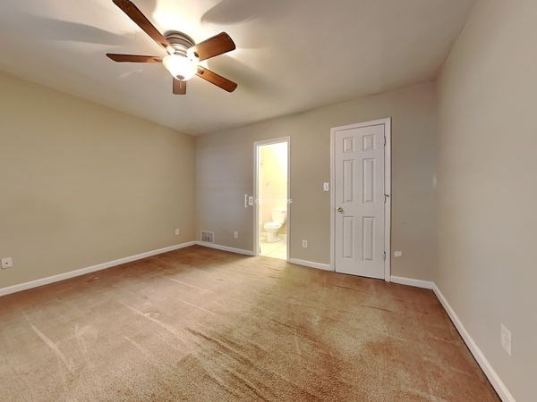 a empty living room with a ceiling fan and a door