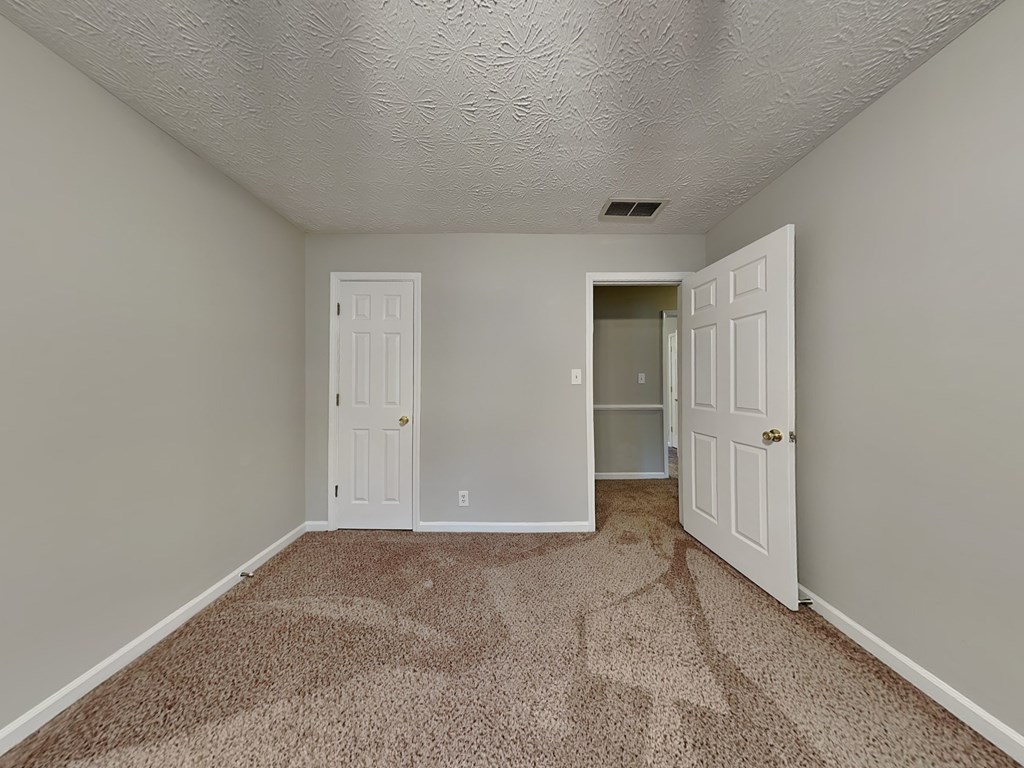 an empty room with carpet and a door to a closet