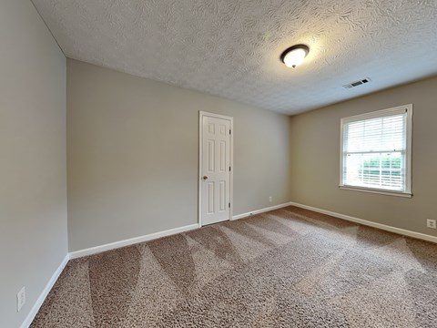 an empty living room with a white door and a window