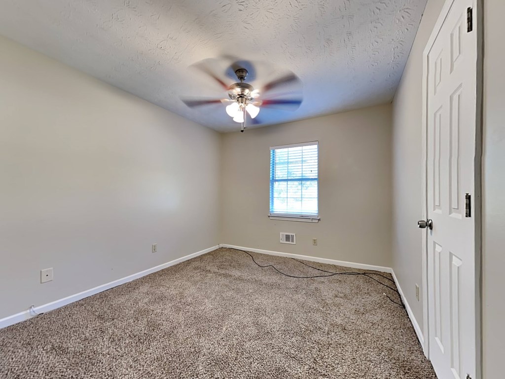 an empty room with a ceiling fan and a white door