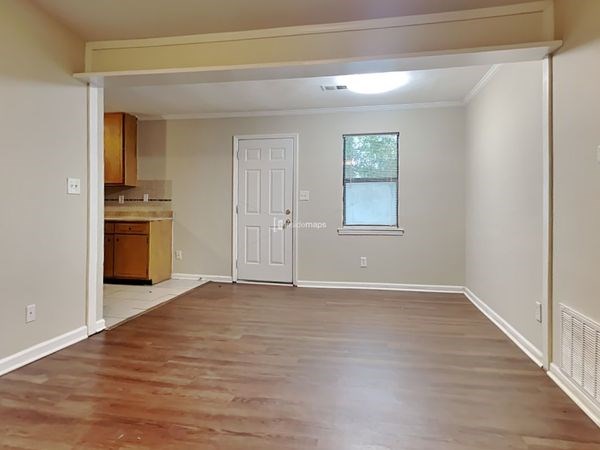 an empty living room and kitchen with wood floors