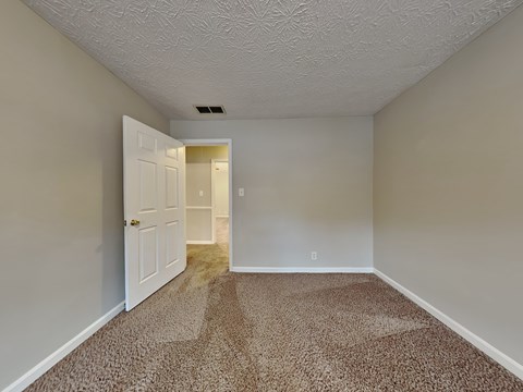 a bedroom with a white door and a carpeted floor