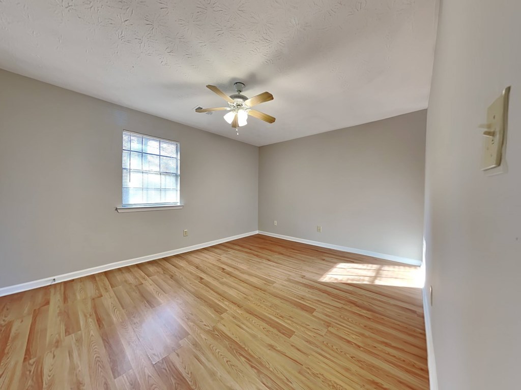 an empty living room with wood floors and a ceiling fan