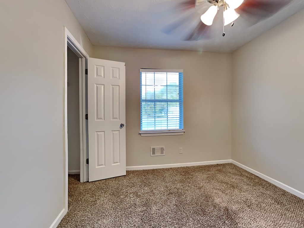 an empty living room with a white door and a window
