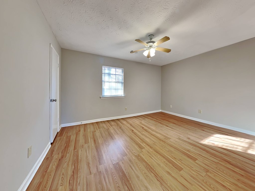 an empty living room with wood floors and a ceiling fan