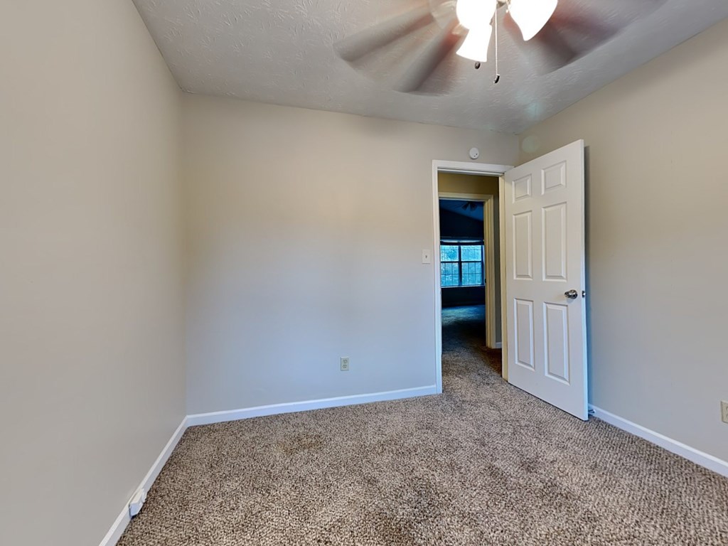 a bedroom with a white door and a ceiling fan