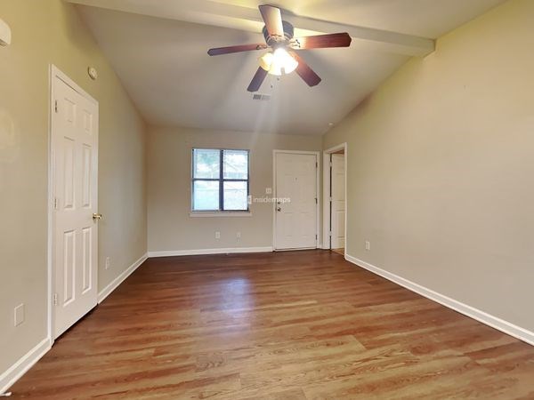 an empty living room with a ceiling fan