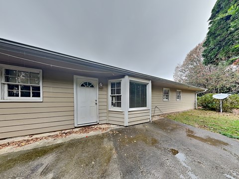 the front of a house with a white door and a driveway
