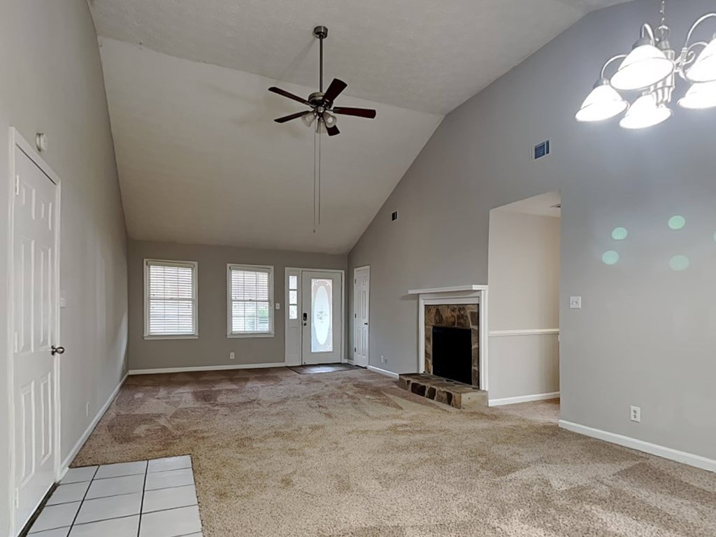 an empty living room with a fireplace and a ceiling fan