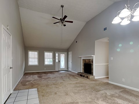 an empty living room with a fireplace and a ceiling fan