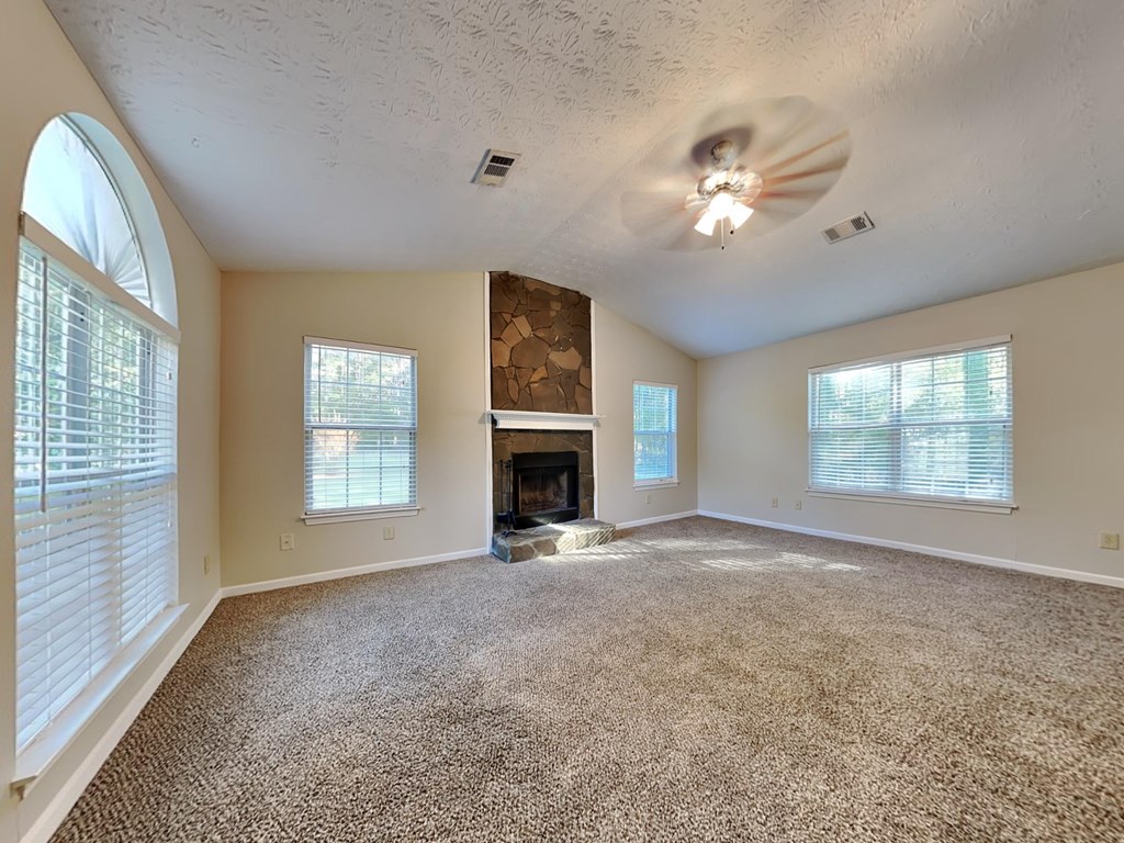 an empty living room with a fireplace and a ceiling fan