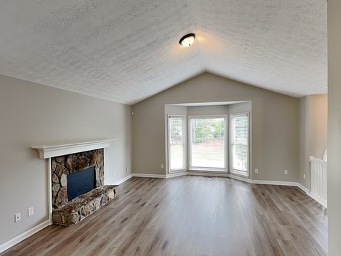 A room with a stone fireplace and sliding glass doors.