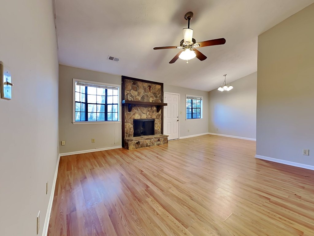 an empty living room with a fireplace and a ceiling fan