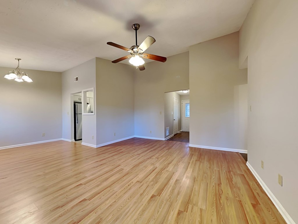 an empty living room with wood floors and a ceiling fan