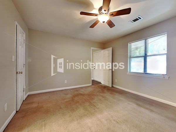 an empty living room with a ceiling fan and a window