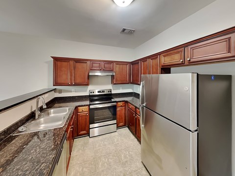 A kitchen with a refrigerator, sink, and stove.