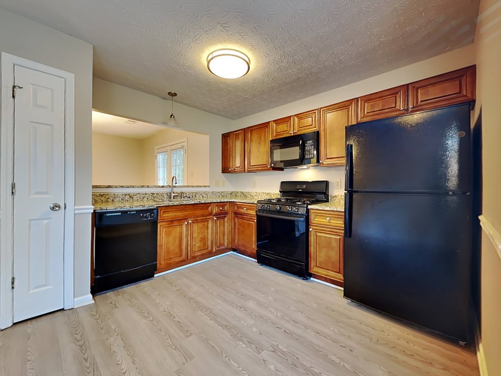 an empty kitchen with black appliances and wooden cabinets