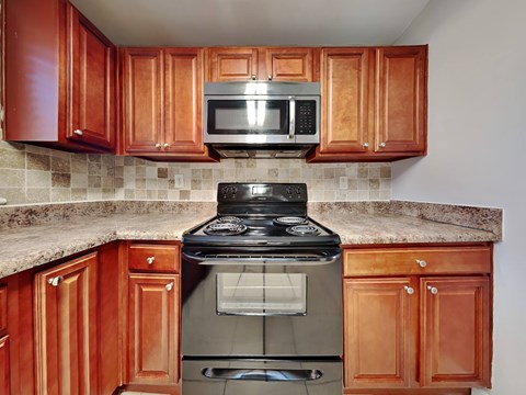 A kitchen with a black stove top oven and a microwave above it.