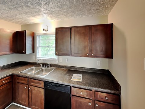 A kitchen with brown cabinets and a black dishwasher.