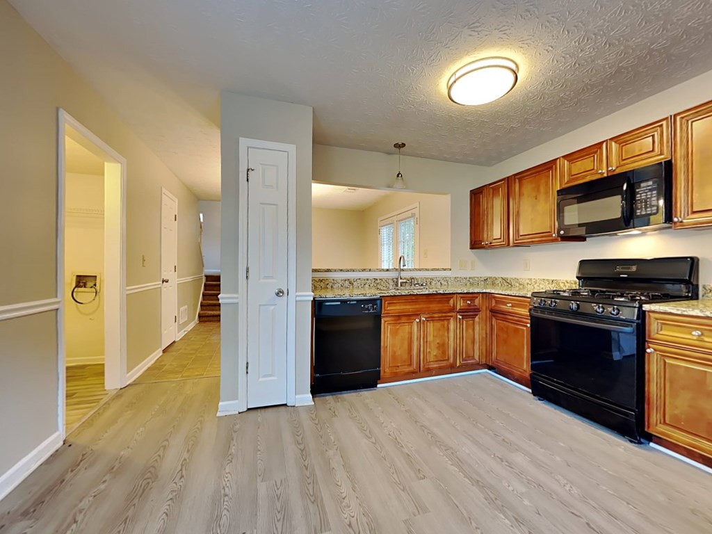 an empty kitchen with wooden cabinets and black appliances