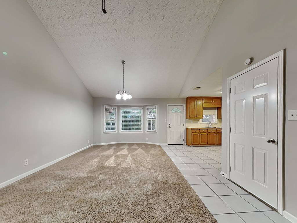 an empty living room and kitchen with a white door