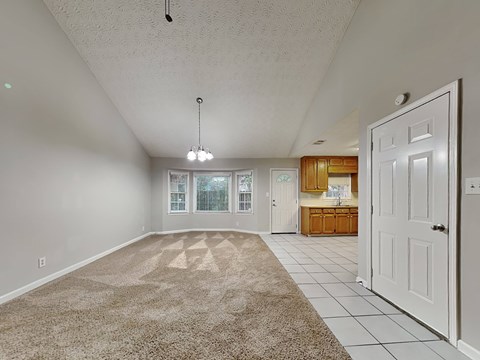 an empty living room and kitchen with a white door