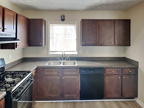 A kitchen with dark brown cabinets and black appliances.