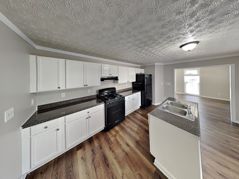 A kitchen with white cabinets and a black stove top oven.