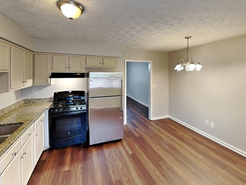 A kitchen with a black stove top oven and a refrigerator.