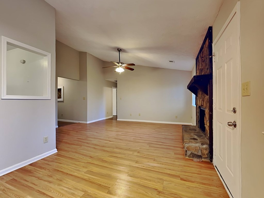 an empty living room with a wood floor and a fireplace