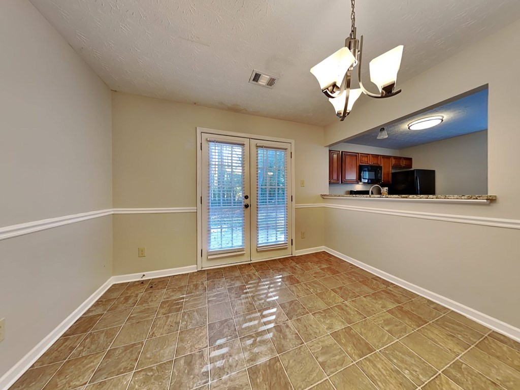 an empty living room with a sliding glass door to the kitchen