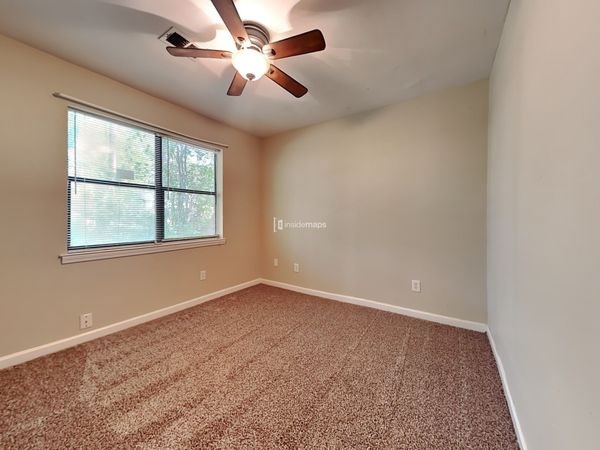 an empty bedroom with a ceiling fan and a window