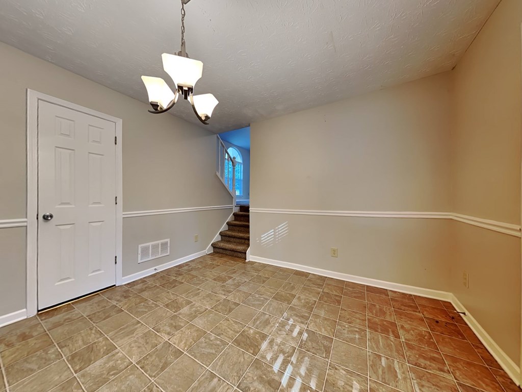 an empty living room with a white door and a staircase