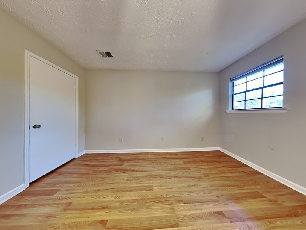 an empty living room with wood flooring and a window