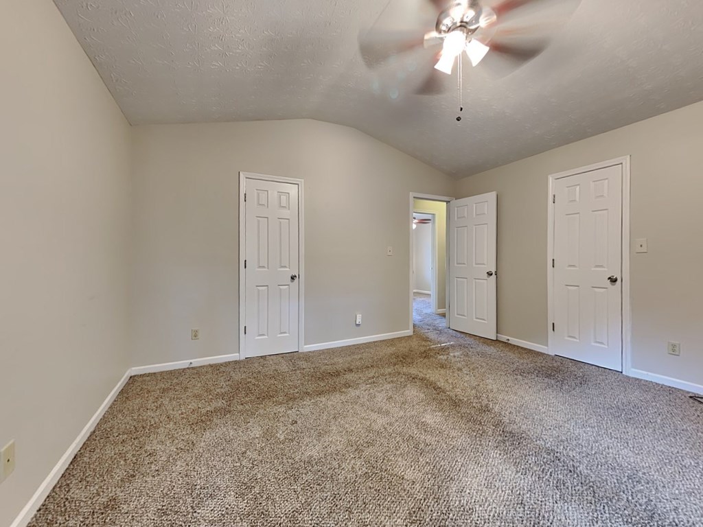 an empty living room with two doors and a ceiling fan
