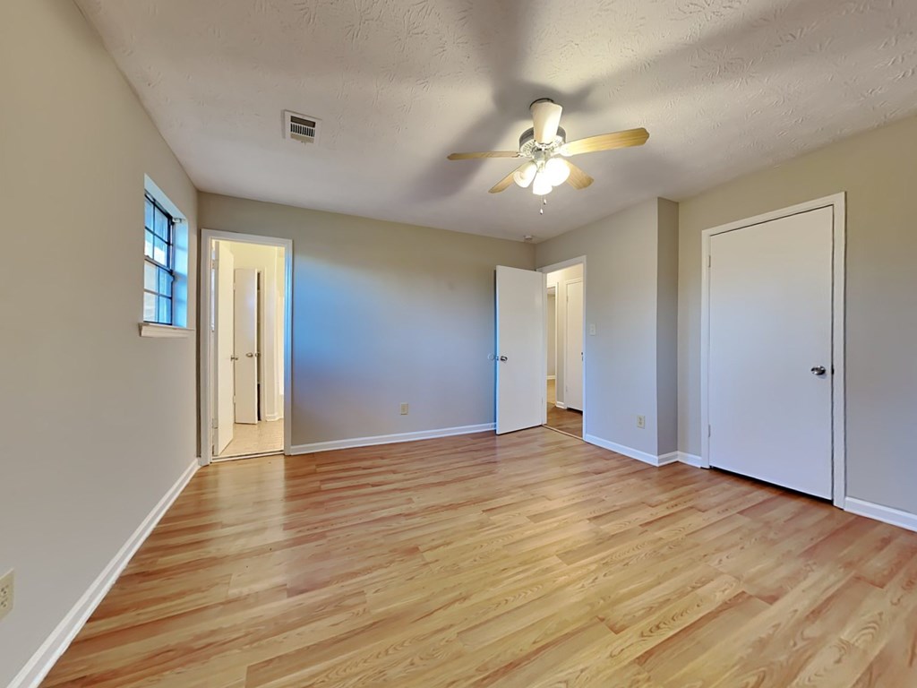 an empty living room with wood floors and a ceiling fan