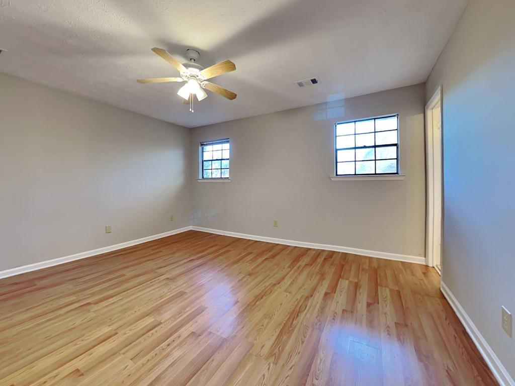 an empty living room with hardwood floors and a ceiling fan