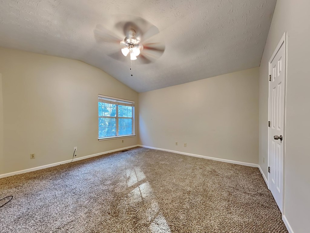an empty living room with a ceiling fan and a window
