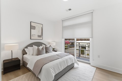 A bedroom with a large bed and a balcony.
