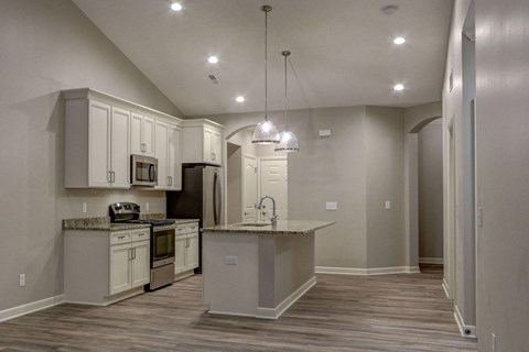 an empty kitchen with white cabinets and a counter top