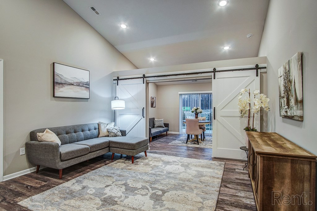 A living room with a couch in front of a sliding barn door in a home at Chestnut Hills.