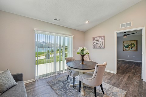 A dining room with a table and chairs and a painting on the wall.