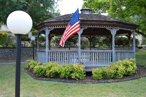 A gazebo with an American flag hanging from the roof.