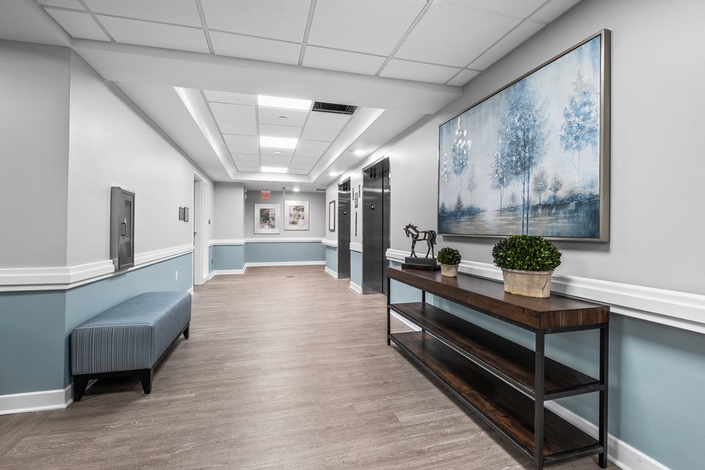 a common area long hallway with a bench and a painting on the wall