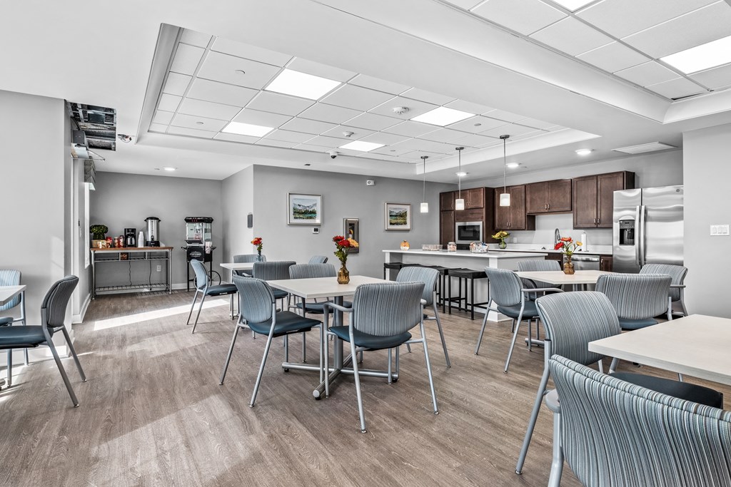 a community dining room with tables and chairs and a kitchen